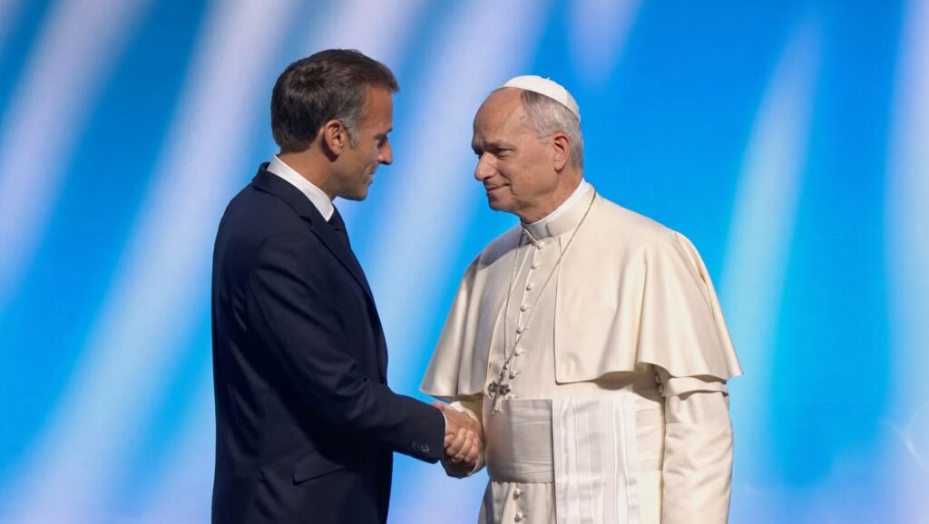 Leo XIV shaking hands with Emmanuel Macron.
